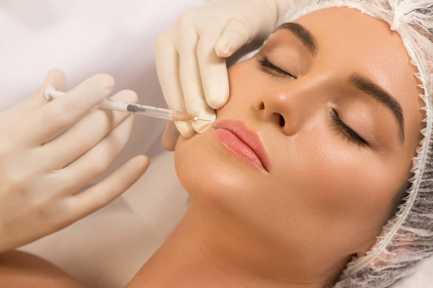Woman receiving lip filler injections at Homa Rejuvenation in Altamonte Springs, FL with a syringe placed into the lips during treatment.
