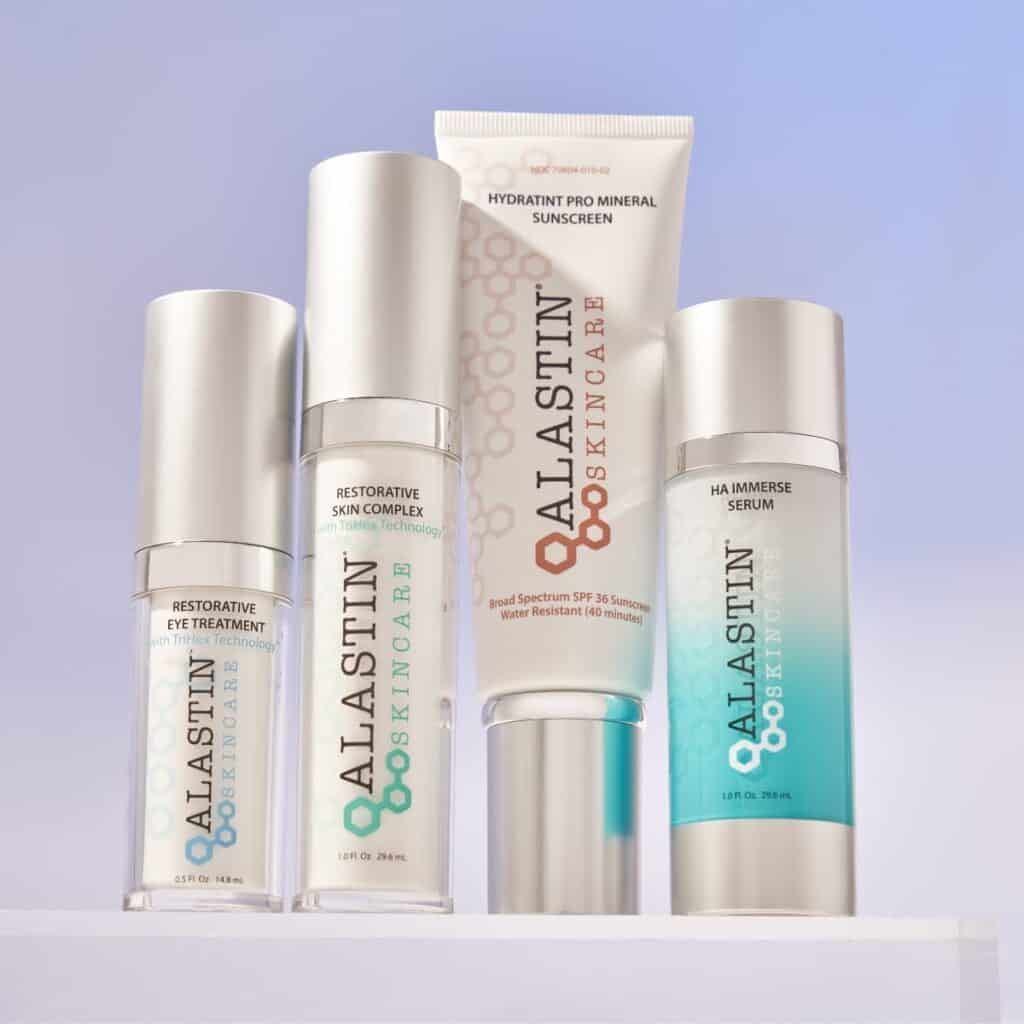 Product lineup of Alastin Skincare at Homa Rejuvenation featuring restorative eye treatment, skin complex, sunscreen, and serum bottles displayed on a clean surface.